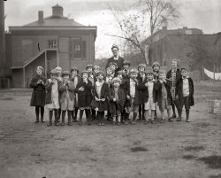 November 5, 1925. "National Apple Week at Washington Orphanage." National Photo Company Collection glass negative. View full size.
Grandma&#039;s placeMy grandmother stayed in an orphanage for a short while, about a year I think, around 1917-1918 when her parents divorced. She never complained about the orphanage or said she was mistreated in any way. She had fond memories of the place. She was 12 and she and her friend would sneak out at night. There was an Army camp nearby and the soldiers would gather around to hear my grandmother and her friend sing for them. A very different world back then.
It&#039;s a hard knock lifeBut at least they have apples. Too cute!
Shortage of male orphansFascinating, this one's a keeper...been gazing at it for ages. What happened to them all? Why 17 girls and only 4 boys? Is there more chance of dying young if you give birth to girls? Is it just the haircuts or are there a fair number of sisters?
Do the TwistGrowing up reading Dickens, the word "orphanage" conjures up a place of poverty-stricken wretchedness. It's nice to see these kids are just...the ones with the apples just hanging in their teeth are amusing. I'm sure the matron behind them didn't know they were doing that! Another thing that stuck out to me was the eerie similarities in the girls -- dress, glasses, hair. I know that they must have all shared one barber amongst the girls and the boys, so he or she had one cut, and efficiently went with it. 
Lucky, lucky girl on the left whose coat fits so well; no one else seems to be quite so well pulled-together. 
Girls&#039; haircutsI would posit the haircuts would have been for ease of care and cleanliness, not that "bobbed" hair was in fashion in 1925.
What a joy.What a joy. Why do we grow up and lose this wonderful sense of play? This photo is a much better advertisement for apples than the "King of Fruit" one.
Relevant Quote"Why any kid would want to be an orphan is beyond me."
-- Miss Hannigan in the movie version of "Annie"
OrphansMy grandfather and some of his brothers were in an orphanage in Davenport, Iowa in the early 30's.  His parents were alive but they couldn't afford to feed &amp; clothe all their children.  All my grandfather (who is an outrageous liar) would say about his time in the orphanage is that Leana Horne was also there!  
Orphan questionsMy mom was an orphan in Woonsocket, Rhode Island.
The hair cut is called the "Dutch Boy." It was preferred by most of the children, because if you wore long hair, you were required to keep it neat.  
Most boys went to work for pay outside the orphanage in which she stayed.  They were more readily adopted than girls because of this.  Even if they were living in the orphanage, they worked.  There were gardens to keep and trades to learn, if not at the asylum than nearby at a farm or apprenticeship.  Girls learned home economics, typing, shorthand and bookkeeping at the orphanage my mother stayed in.  Lessons also included "Fannie Farmer" cooking and dress-making.  Scholarships for business school and nearby colleges were available to those with aptitude.
(The Gallery, D.C., Kids, Natl Photo)