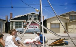 From circa 1958, a Kodachrome taken by my mother, who could handle a 35mm camera in a pinch. My parents had friends with a summer place in Seal Beach, California, a coastal community  on the border of Orange and Los Angeles counties. In the foreground are my parents' bosom pals who owned or rented the place behind the Ford station wagon. That's me at the bottom of the slide; the boy making his precarious way up is the son of the aforementioned couple. Dad (with the cap) appears to be zoning out, judging by the beer cans by his side. I wonder if any of these beachside homes exist today. View full size.
Mad Dog, I am sure you are correct. It is my mother's recollection that the location was Seal Beach. That memory of hers is no doubt a bit hazy, as over 50 years have gone by.
My parents (and I) would visit those friends, and stay at that place several times in the summers of the late '50s and early '60s. I don't know what eventually became of that house.
Years later, I lived and worked in Huntington Beach and would often grab a late night dinner at the Harbor House Restaurant in Sunset Beach. Yummy!
Those were the daysMy grandfather had the same Ford wagon, but his was burgundy with beige.  I loved riding in that car!  If I recall, his was a '54.  I would love to find one and restore it as a daily driver.  I remember it had 3 on the tree. We used to go to the drive-in movies, me and my siblings all decked out in our PJ's, with popcorn &amp; Coke. I remember seeing Dr. No in 1962 at the drive-in. Thanks for the trip down memory lane.  Love the site!
Sunset Beach or SurfsideI just checked an aerial shot of Seal Beach from 1958, and I can't match this photo with any of the beachside buildings. This is probably Surfside (or Sunset Beach), a small enclave immediately south of Seal Beach across Anaheim Bay. 
Surfside is officially part of Seal Beach, but it is now a gated community and has always maintained a separate identity from Seal Beach. Sunset is right next to Surfside. 
The sandy area with the slide is probably on what used to be the Pacific Electric right of way. The red car trolley use to run down to Newport Beach along this strip. 
Seal Beach is celebrating its centennial next year, and you can see more photos of our local history at sbfoundersday.wordpress.com. I'm tickled to see this photo because Shorpy was the inspiration for our blog back in 2010. Kinda brings the whole thing full circle.
Eastside, SurfsideI shared this link to some Seal Beach and Sunset Beach facebook groups, and I'm sure someone in the online mob of locals will be able to pinpoint the exact location, and I'll share it here.
Aha, while I was typing, I got a confirmation that it is in Surfside, and the house on the right is still there and painted blue. I'll try to take a photo when I drive up to SB on Friday, and I'll post it (no Google Streetview, darn it.) Since Surfside is within Seal Beach city limits, your mother's memory was correct!
This photo has made a lot of locals happy. Thanks for posting it.
What brand of beer?On what brand of beer was your father zoning out?  I don't recognize the design on the cans.  Does anyone recognize it?
Looks likeSteinbrau Pale Dry
Surfside I thinkI went to Cal State Long Beach and in those days a lot of these cottages were rented to collage students and my best friend and some others rented a place that looks pretty much like this one. A great little town that tended to flood under large wave alerts.
(ShorpyBlog, Member Gallery)