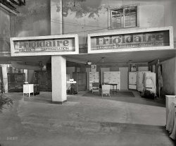 Washington, D.C., 1926. "Industrial Exposition, Frigidaire." A chilling display at Washington Auditorium. National Photo glass negative. View full size.
Doesn&#039;t look very &quot;corporate.&quot;The obvious damage to the negative doesn't help, but the shabby look of the building, the worn and weathered looking signs, along with the dingy look to the whole scene makes it look pretty low-rent for a subsidiary of GM. The General had owned Frigidaire for some years by the time this was shot. Lots of interesting things to look at, though. The frosty signs are neat, and do look like something a GM division would supply.
DismalThat is an extremely dour array of appliances.
Fascination I'd sure like to climb into the Wayback machine and go to this showroom.  Early refrigeration systems interest me.  1926 was before DuPont's introduction of Freon. In 1930, General Motors (owner of Frigidaire) and DuPont formed the Kinetic Chemical Company to produce Freon.  It would take about 80 more years for science to condemn Freon as an environmental evil.
I wonder how often they defrosted those icy displays?
Frigidaire became a generic nameI remember when regardless of the brand of refrigerator you owned whether it be a Crosley, Admiral, or Westinghouse, it was always referred to as a "frigidaire" since it was one of the earliest and most dominant brands.
It's the same with "Jello" and "Kleenex". They were first so their brands became the generic name for their type of product.  Is Royal pudding even made anymore?
Cool!I love the coolant tube demos covered in frost!  I also need that center four-door white enamel number.That would be fantastic in my kitchen.
A Brrr-illiant Idea!Back in the Forties we had a Frigidare refrigerator. It even had a light inside which came on as the door was opened. A miracle to children, some of whom could still remember when homes were lit by oil lamps. Our "Fridge" was a newer postwar version than the models shown in yet another fascinating photo from Mr. Dave.
The motor and compressor, by then, were a single enclosed rotary unit that hummed away happily until well into the Sixties. Like all mechanical cooling devices of the era, it was a real chore to defrost with pans of water dripping as you moved them to the sink with melt from the iceberg above.
We were fortunate to have a Fridge, as many still had ice delivered in block to their Ice Boxes, this ice delivery lasting into the Fifties. (The pantry in our home had a drain in the floor expressly for the melt from an icebox; my father had the washing machine installed there to use the drain.)
The new Fridge stood proudly in the kitchen, next to the gas stove still lit by wooden "Strike Anywhere" matches from their holder handy by.
The block ice for ice boxes came by truck when bread and milk still arrived in wagons behind horses. Coal and coke for heating and hot water, by then, came by truck, but some districts still had horse wagons for bag coal, wood and kindling. We had a fireplace set up for coal burning, but it was never used.
Note the clever advertising displays to the right, showing the motor and belt-driven reciprocating compressor and the cooling unit above in a pyramid-like rack. The belt-drive compressor versions were noisier and went clunk-clunk-clunk, their motor and compressor often situated on top of the cooling compartment to access the belt and for cooler operation.
The Brilliant Idea is the word Frigidare written in frost on a cold pipe just to the right of the column in the photo. A Brilliant concept, and housewives could see and touch the cooling action, possibly clinching a sale?
[The potential customers at this industrial exposition were more likely restaurant and hotel owners. - Dave]
&quot;Royal Pudding!&quot;"Rich Rich Rich in Flavor,
Smooth Smooth Smooth as Silk,
More Food Energy than
Sweet Fresh Milk!"
(I also haven't seen that on grocery shelves in many years.)
KineticAfter Kinetic Chemical Company did well with Freon, they changed their name to Kinetic Freon Company, and then later to just KFC.  Ironic, but today cold chicken stays edible only because we have modern refrigeration.  
The compressor on the rightis larger than the engine in my Corolla.
Free he die reeis how Hispanics pronounce the brand name Frigidaire when they mention a refrigerator. In many Spanish speaking countries, this is what a refrigerator is called by.
Something&#039;s missingWhere are the potted palm trees?  It seems like every trade show booth in the 1920s had some.  Did the Frigidaire people forget to order them?
Too cool!So this might have been the inside of the Delco-Light showroom that I incorrectly associated with 32-volt rural generators.
[The location is Washington Auditorium at 19th Street and New York Avenue. The Industrial Exposition, held March 4-13, was hosted by the D.C. Chamber of Commerce. - Dave]
From what I have read, this is about one year before domestic refrigeration hit the tipping point, where the entire middle class either had it or was on their way to getting it. Kind of like I-Pods a couple of years ago.
I've never seen a showroom photo from this era. I find the open evaporator coils very fascinating. They would have been impressive at the time, all of those small ice crystals you could touch. A generation later, this wouldn't have been a selling point. By 1956, automatic defrost was the new thing. People were tired of defrosting, and visible frost would have been a big turnoff!
And yes, the flip side of the Freon comment is the refrigerants in use before Freon. Methyl formate and sulphur dioxide were the choices. Both of these were highly toxic. If inhaled, the gases reacted with water to form strong acids that would burn the lungs. Thomas Midgely, the inventor of Freon, made a public demonstration of inhaling the gas and then blowing out a candle, so well known was the hazard of the earlier refrigerants.
Note that these Frigidaires have belt-driven compressors. That means a shaft seal that can leak. The GE Monitor Top, which hit mass production in 1927, was the first to have a completely sealed compressor, with the motor immersed in the refrigerant. These cannot leak unless pierced, and all refrigerators today use this design.
DefrostingThey defrosted the same way my mother did in the 1950s. You shut it off and left the door open (if it was not already open). You put in pots of hot water to hasten the melting. You put old towels on the floor to catch runoff. You became impatient at the mess and day job and you chipped at the frost on the coils. Then if you punctured a coil and the freon began escaping, you cried. Then your husband bought a new one. 
Yes, there is a brand of pudding marked "Royal" but who knows if it is the same Royal, or where it is manufactured. 
This photo looks like sub-basement storage, a "long after the affair has ended" type of deal. The wicker chairs are where the workmen sit to eat lunch and play a few games of rummy. Of course the moldy negative may be leading me in the direction too.
Interesting photo. I like it. 
So ColdThat even the glass negative got frostbite.
It sure looks worn out for being so newA little history on the Washington Auditorium. This is one place I had no idea ever existed until now.
Frigid AirThe name Frigidaire was so entrenched in my mind a as refrigerator and corporation that it never even occurred to me until about 3-4 years ago that it stood for "frigid air." That was one of those "DOH!" moments.
RefrigeratorAs said, some people refer to refrigerators as "fridigdaires." Our next door neighbors had a Kelvinator brand refrigerator which was always referred to as the "kelvinator."
My family bought a new house in 1932. Would you believe a new house at the depths of the Depression? Well, we had several incomes -- my mother and father, aunt and uncle, grandmother and her unmarried sister all lived there with me as the only child. The house had out first electric refrigerator -- a GE with the sealed cooling coils on top.  No more putting a sigh out for the ice man -- 15 lb or 30 lb.
[So Mom missed the iceman's visits, did she? - Dave]
What I like most ....is the price tag on the chair!
From a former Frigidaire dealerAn educated guess, 25 percent of our Frost Free (as opposed to Self-Defrost) refrigerator/freezer sales came because someone poked a hole in the refrigerator coils with an ice pick or screwdriver whilst trying to manually defrost the unit.
(Technology, The Gallery, D.C., Natl Photo)