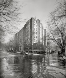 1926. "W.H. West Co., Wakefield." Wakefield Hall was  "an imposing new apartment edifice" put up by W.H. West Co. at 15th and V streets N.W. in Washington. Rents: $60 to $160 a month. National Photo Co. View full size.
It rains only on one block of the street?Why is only part of the street wet, and none of the sidewalk? Clearly it isn't from rain, but what would it be from?
[Street cleaning. - Dave]
Sky-high Rents$60 to $160 a month was hugely expensive in 1926. The tenants must have been very well off to afford it. In most cities and towns in the 1920s and 30s one could rent a nice two-bedroom house with a yard and a garage for $20 to $30 a month, and frequently less. In the mid-1930s, my dad paid $15 a month for a comfortable house in Casper, Wyoming (not Washington, for sure, but fairly crowded with oilfield crews and railroad workers). He could easily afford it because he was making $75 a month as a telephone lineman.
Still there......and looking much the same, although the street scene has changed a lot over the past 83 years.
View Larger Map
Not So Sky-High ActuallyRent at $60 would just top a bit over $700 today, which for an urban location, no matter what city, is actually a bargain. There may have been a number of choices in the gap to $160 also, and many people today would jump at the chance to have that low a rent! Murphy beds and fold-in ironing board as well as dumbwaiter garbage collection and a doorman were in fashion &amp; high regard and the smart set would be flabbergasted with these digs.
Still there and still a rentalThough now, instead of sky-high rents, it's a rent controlled building.  The church in the background is still there, too, but the steeples are gone.
GhostsWe regularly see ghost people, but I think that this is the first time I recall seeing a ghost truck in a Shorpy photo.
[That's a person crossing the street from the corner on the right. His hat is in front of the delivery van. - Dave]

(The Gallery, D.C., Natl Photo)