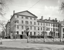 New Haven, Connecticut, early 1900s. "New Tontine Hotel, Church and Court streets." 8x10 inch glass negative, Detroit Publishing Company. View full size.
Street lightFound the light fascinating. Wiring from the pole and then a cable and pulley system to raise and lower the light itself. Amazing contraption.
[It's an arc lamp. - Dave]
All gone, except the Green.From "Leading Business Men of New Haven County" (1887, Wm. Hale Beckford):
The hotel building is a substantial four-story structure, on the corner of Church and Court streets, opposite the Yale College grounds or "Green."  
Tbe cuisine is unexceptionable, the aim of the prudent landlord being to supply everything calculated to tempt the appetite, and to serve the viands in a manner calculated to please the most exacting bon vivant. Every modern appliance and convenience has been provided, and a stay at the "Tontine" will ever be remembered by the guests of Mr. Bradley as the most pleasing experience and feature of a visit to the Elm City.
The fence is still thereView Larger Map
A perfect view of how the arc lamps were used.This picture clearly shows the pulley mechanism for the servicing of the electrodes and the cleaning of the globe. 
Dave, if you ever come across a shot of an arc lamp being serviced, please share it with us. 
Arc lamp serviceI think the photo was taken in Colorado. The blanket on the hood of the Model T service truck tells us it's winter. I love the block of wood the electrician is standing on, to insulate himself from ground!

Interesting name for a hotel A Tontine is a scheme for raising capital which combines features of a group annuity and a lottery. Each member in the group puts an agreed upon sum into a pot, and upon the death of every other member, the last person remaining collects the pot.
(The Gallery, DPC)