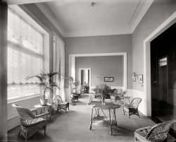 Lake George, New York, circa 1908. "Ladies' parlor, Fort William Henry Hotel." 8x10 inch dry plate glass negative, Detroit Publishing Company. View full size.
As opposed tothe men's smoking room?  I want to see a picture of that one. I guess this is where needlework was done.
Got a Light?I'm underwhelmed by the ceiling light fixture. You would think the room deserved better. Maybe because the windows are so large artificial lighting wasn't a priority.
It was all ashes very soonThe carpet looks new and the paint looks fresh.  $30,000 was spent on refurbishing before the hotel opened for the 1909 summer season.  Shortly after it did, it was destroyed by fire on June 24.
The replacement lasted longerA replacement hotel arose very quickly in 1910-11 and lasted until 1969 when the summer resort trade fell off and competition from newer (and cheaper) motels hurt the business. Two large fragments survived -- the service wing and the elaborate main dining room, which was made into the wing of a motel. Both these fragments have been incorporated into a recently built hotel and conference center which claims to "closely replicate" the 1910 building. Which it sort of does, in a cheap way.
Just say noto Wicker furniture! 
What is that on the table?Most of the decor looks pretty bland to me, with the exception of the critter hide stretched out on the center table. I'm just not seeing it - wicker, white curtains, and ... leather? Weird. I guess someone got a good deal on it.
Blessing in DisguiseAs someone who has an entire bedroom set made of wicker, I truly feel for the maids who had to clean it. That junk is nearly impossibly to keep clean, tiny crevices galore. 
(The Gallery, DPC)