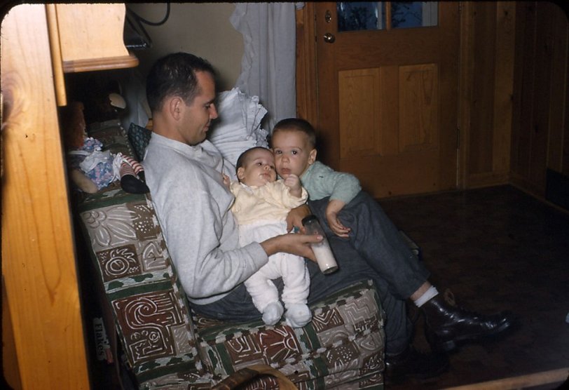 Another 35mm slide from the farm, 1956. Raggedy Ann is seated on the back of the settee. Dad has just fed George and I am about to dose off. View full size.
