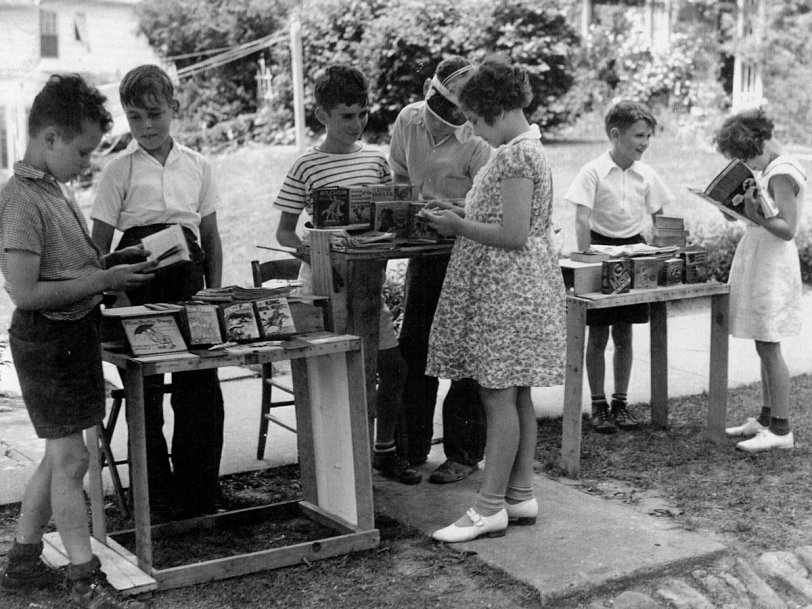 That's my late sister in the center foreground, about to purchase a "little big book" from neighborhood vendors at this makeshift curbside bookstore on Bush Avenue in Newburgh, NY in the summer of 1937 or 1938. The girl browsing the comic book on the right is our cousin. View full size.
