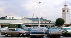 Los Angeles, March 1969. Farmers Market and CBS Television City. Does this viewpoint look the same today? I haven't been back since. Love the Linen truck in the lot. View full size.
It pays to keep cleanIn the same era but a world away from California in Winnipeg, Manitoba, I recall seeing those very same trucks as a kid.  No doubt they dealt with bed linens, hotel towels and uniforms, but what I noticed them delivering were those rolls of cloth towels used in public washrooms.  Extremely few of those are left nowadays, although I know one place that still uses them.  Remember when the towel came to the end of the roll and you'd be left with the gross, damp, filthy end hanging from the spool?
A Few Years EarlierYou asked if the view would be the same today. I don't know, but I do know that the view would have been different a few years earlier - say in 1956 - because Television City wouldn't have been there. Instead you would have seen Gilmore Field, home of the Hollywood Stars of the Pacific Coast League and Gilmore Stadium, an oval football and auto racing venue that hosted the NFL Pro-Bowl game in 1939 and 1940.
Once So CommonIt's always interesting to look at a picture like this and recall how all those vehicles were once everywhere in my life.  Some of them I never see anymore, even at an antique auto show.
(ShorpyBlog, Member Gallery)