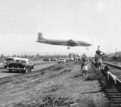 Greg Herbert remembers piling into the station wagon and the family heading down to LAX. They would make it an outing just to see the planes land. You used to get pretty close to the runaways before they built the big fences. Photo taken 1950's by Mary Herbert.
I remember watching the planes land, tooIt was in Birmingham, Alabama, though, not LAX. There used to be a road that cut across the flight path between the end of the runway and a line of light installations to guide the planes at night. On occasional Sunday afternoons we would go down there, pull off the side of that road and watch a few planes fly overhead. That was in the early- or mid-1960s. They closed that road to the public well before 1969 when we moved away.
The airplane is an American Airlines Douglas DC-7, possibly a freighter converted from a passenger version.  This is the "two-five" complex, or south complex where the two runways are 25 Left and Right.  The scene in the 1969 movie "Easy Rider" where Fonda makes the deal with Phil Spector (in his Rolls) was filmed right about here, behind the jet-blast deflectors that are still there.  The north complex (runways 24L and R) was constructed in the very early 1960s.
Crazy CaliforniansBoy you folks out there sure do things differently from the rest of us. I did a lot of flying in the Army and afterwards and thought I knew about airports. Runways are generally numbered according to the compass heading on approach, meaning they have reciprocal numbers at each end adding up to 36 (360 degrees). Not LAX!
According to the airport map, the two runway pairs are 6-24(R,L) and 7-25(R,L), neither of which adds up correctly.
Anyone know the answer?
Those runway numbersThose runway numbers are correct. 
It's not that the two number add up to 360, but that there's 180 degrees between the two headings. So, for runway 6-24, subtract 60 from 240 and you get 180. The same for runway 7-25: 250-70=180. 
CrazinessThank you, Mike-76NYSV for correcting my miscalculations. I knew the runways were straight and they haven't changed the compass since I last used one. It must be my brain that's the problem!
(ShorpyBlog, Member Gallery)