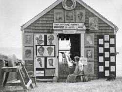 This was taken in Provincetown, Massachusetts. All I know about it is the year and location. Scanned from the original 4x5 inch acetate negative. View full size.
Air Conditioned?1936 seems a little early for a dune shack to have electrical air-conditioning.  Flow-through ventilation looks to be more likely.
"In 1945, Robert Sherman of Lynn, Massachusetts invented a portable, in-window air conditioner that cooled, heated, humidified, dehumidified, and filtered the air. The idea was subsequently stolen by a large manufacturer. Sherman did not have the resources to fight the big corporation in court and thus never received any money or recognition. He died in 1962."
[The AIR CONDITIONED sign is an early humor app known as a "joke." - Dave]
Ten Gallon VeepThe caricature in the cowboy hat is the then-current U.S. Vice President and prominent Texan, John Nance Garner.
I spy with my little eyeGarbo, Jean Hersholt, Cab Calloway, Lionel Barrymore, Rudy Vallee, Katharine Hepburn, Jimmy Durante, Tallulah Bankhead, Ed Wynn, and at the top are Joseph, Benito and Adolph. The others I can't recognize.
Name that caricatureHere are my guesses:
Top row, left to right: Josef Stalin, Benito Mussolini, Adolf Hitler. Left door: top row, ? and Mark Twain; second row, Little Richard(?) and Rudy Vallee; third row, ? and Katherine Hepburn; bottom, Jimmy Durante. Right door, from top: George Bernard Shaw(?), Joan Crawford, Ed Wynn(?)
[A teensy bit early for Little Richard. -tterrace]
Famous facesTop row: Garbo, W. C. Fields (?), Eugene O'Neill, George Bernard Shaw.
Middle row: John L. Lewis, Eleanor Roosevelt, Rudy Vallee, Joan Crawford.
Third row: George Arliss (?), Katherine Hepburn, FDR.
And of course the great Schnozzola!
And the last one...Just above and right of the door looks like Snuffy Smith's wife, Loweezy, from the Barney Google and Snuffy Smith comic strip.  Copyright laws then must not have been as protective of such characters as they are now.
Art ColonyThis was the artzy, bohemian and rustic Provincetown.  A Provincetown where you could escape the city for the summer or live all winter on a dime. Many writers and artists sought refuge in this accepting fishing village at the end of Cape Cod. 
In recent decades the wealthy have invaded.  They like living in art colonies but have little tolerance for edgy characters that are a staple in any art colony.  They have been driven away making the town safe for big spenders. 
Today it is a real estate investment.  Houses cut into a half dozen condos at 400k each, big city rents, parking meters that take credit cards and very high taxes.  
Those fading character sketches can still be found on display in the Mayflower restaurant on Commercial street. 
What the?!?What, possibly, in 1936, could the artist mean by the threesome labeled Faith, Hope, and Charity?  Was the artist a socialist?
[I believe it's called "satire." -tterrace]
Famous facesMaybe Charles Evans Hughes instead of G. B. Shaw? 
WonderWho 'D_Chadwick' was.
[It is this person. -tterrace]
Glad I have the time to repent at leisure 
The DukeI think this is supposed to be Duke Ellington, the monocle a visual pun on his aristocratic nickname. 
re: WonderI'm D_Chadwick and I'm not a "was" yet I'm still an "is".
As a matter of fact I'm getting better. I think I'll go for a walk.
Why the termMurdered? What did that mean in slang terms then? Now the kids all "Murder Out their Ride". *Paint the vehicle matte black everywhere including rims and trim. But then, in Pastel?
[Ruin, butcher, mangle. For example; "The tone-deaf singer murdered the song." Another joke by the caricaturist. -tterrace]
The artist Possibly Richard Miller?
[According to his sign, his name is Wheeler. -tterrace]
More of the artist&#039;s portraitsThis auction house appears to have sold some of the artist's portraits. Note the tall R in his signature.
(ShorpyBlog, Member Gallery)