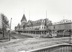 Mount Clemens, Mich., ca. 1899. "Egnew Hotel." Connected to THE ORIGINAL BATH HOUSE across the street. 8x10 inch glass negative. View full size.
Burning and Bathing Go hand in hand at least in the history of this establishment: http://www.mtclib.org/local%20history/original%20bath%20house.pdf
The Egnew"The scene of all this gaiety was to burn later--the fate of many of Mount Clemens's early hotels, most of which were of
frame construction." - Prior to 1910
And here's a photo of the other end of the elevated walkway.
I wonder...when it burned?
Wood RoadInteresting road construction being logs placed in the ground vertically as opposed to a typical horizontal plank road.  I can't remember the term for this type of construction.  Maybe someone else knows.
Battling BathersMt. Clemens' days as a bathing resort may be far in the past, but they are still remembered there in the sports teams of the local high school, who are known to this day as the Mt. Clemens Battling Bathers.
(The Gallery, DPC)