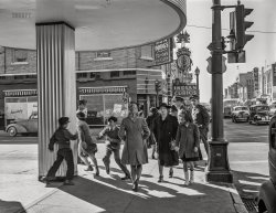 February 1943. "Albuquerque, New Mexico. Central Avenue and Fourth Street." Acetate negative by John Collier for the Office of War Information. View full size.
Central Avenue is part of Route 66Or was. 
Love all that neonI can only imagine what that Indian Curios sign looks like at night. It's a beautiful piece of work.
Follow the rabbitDidn’t Bugs Bunny forget to turn left at Albuquerque?
Damned Kids!Says the lady in black.
The Most Beautiful Girl ...   63 years ago we were following Route 66 heading east on leave and we stopped in Albuquerque for a bite to eat. The waitress we had was one of the most beautiful ladies I have ever seen in person and today she is still in the top 3. She was about my age (21), long curly red hair, green eyes, shapely form from head to toe and the best part was the warm friendly smile she gave to three travelling sailors.
   I was smitten and if I hadn't been heading home to ask my girl there to marry me I might have stayed in Albuquerque to pursue this vision of Irish beauty, Riona. I ate slowly to prolong my time there so much my two travelling buddies said to eat up or we are going to leave me here. I was torn between this lady and the lady I did know and love in Baltimore.
   Common sense did finally prevail and I headed back east to my Dorothy to get engaged to one of the other top three beauties in my life. We had a good life together but once in a while I would lean back in my easy chair, smile and pull up the memory of my short time with Riona.
+72Below is the same view from July of 2015.
Indian CuriosMaisel's Indian Trading Post opened in 1939 on Route 66 and lasted eighty years. The photos below show its heyday and diminished later years. There are still plenty of souvenir shops (Indian curios, yes, and also the Breaking Bad Store); but you should check out the Indian Pueblo Store owned and operated by the nineteen Pueblo tribes.
The Lady in BlackAlthough she seems to disapprove of the boys' antics, her companion, Cowgirl Carrie, looks rather amused by them.
Two sizes upLittle Missy who is enjoying watching the roughhousing boys so much is going to need a new coat by next winter. She's well fixed for boots, though.
NostalgiaAs an Albuquerque resident, I wish the downtown was still as vibrant as it is in this photo. Fortunately, the KIMO Theatre is still there and presenting plays and concerts. Unfortunately, Skip Maisel's Indian Curios closed several years ago. I treasure the jewelry I purchased there over the years. Fine craftsmanship. Thanks for this glimpse into the past.
BackgroundMaisel’s Indian Trading Post, which opened its unique John Gaw Meem designed building in 1939, was closed permanently in August, 2019. The building is listed in the National Register of Historic Places and efforts are being made to try to preserve the historic Native American murals on its elaborate Art Deco facade.
https://www.newmexicomagazine.org/blog/post/maisels-indian-trading-post-... 
(The Gallery, Cars, Trucks, Buses, John Collier, Kids, Stores & Markets)
