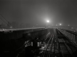 March 1943. Kansas City, Kansas. "Argentine Yard, Santa Fe R.R. -- Night view of the departure yard on the route of the Atchison, Topeka and Santa Fe Railway." Previously seen here, in color. Acetate negative by Jack Delano for the Office of War Information.  View full size.
Light BriteOn the left the lantern or flashlight of a RR worker creates a streak of light passing the train cars.  You can get an idea of the exposure length.
Long ExposureLong enough for that carman to walk past at least 8 cars to check out what looks to be brake hoses, door latches, and whatever else.
(The Gallery, Jack Delano, Railroads)