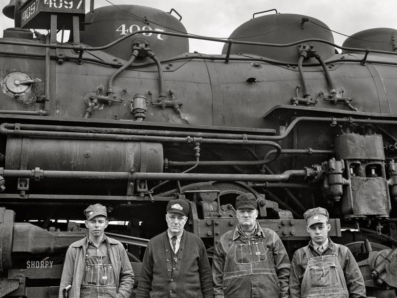 March 1943. "Wellington, Kansas. An Atchison, Topeka and Santa Fe Railroad crew posing in front of their engine before pulling out of Wellington for Waynoka, Oklahoma. Left to right: D.C. Quivey, head brakeman; D.B. Wallingford, conductor; B.F. Hale, engineer; and fireman Walker." Acetate negative by Jack Delano for the Office of War Information. View full size.
