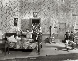 &nbsp; &nbsp; &nbsp; &nbsp; "Permeated by the passionate, vengeful Neapolitan spirit, despite a pleasing lack of half-intelligible broken English."
-- New York Times

New York, 1902. "Scene from Little Italy showing Minnie Maddern Fiske on bed, Frederic De Belleville kneeling, Claus Bogel seated with head bowed, and group of people in doorway." Little Italy, a "one-act tragedy of the East Side" by Horace Fry first performed in 1898, was revived on Broadway in 1902 for a 24-performance run at the Manhattan Theatre. Joseph Byron photo. View full size.
Lost Episode of The HoneymoonersAlice has overslept. Ralph and Norton and the neighbors are distraught. 
Revelant if not relevantHigh Mediterranean melodrama, and not an Italian name among the featured players.  Except for such classical artists as Caruso and Adelina Patti, performers of Italian ancestry had yet to make much penetration into the lively arts in this country.
Here, Italian immigrants are apparently the objects of patronizing sympathy ... poor, benighted souls!  Primitive, true, but they seem to feel pain almost like a real person.
Within two decades, however, the age of Valentino and Ted Fio Rito and Toscanini and thousands of others will dawn.
Passion Indeed!The knife on the floor explains the whole scene.
Garlic on the wallWhat an interesting set!  That quilt on the bed is incredible.  I wish we could see it in color. I'll bet every stitch was put in by hand! 
The garlic hanging on the wall is a nice touch, too. Were they planning to make sauce for their cast party at the close of the play, or were they keeping vampires away?
Mrs. FiskeStage actress Fiske also appeared in two silent films, "Tess of the D'Urburvilles" (1913) and "Vanity Fair" (1915). The acting style of a bygone era is referenced in "All About Eve" when Eve Harrington flings open the door and demands that Addison DeWitt get out, to which he blithely replies, "You're too short for that gesture. Besides, it went out with Mrs. Fiske."
FamiliarLooks something like the Italian drama portrayed in the first part of the first "Godfather" movie.
A brief reprise"Little Italy" last appeared on Broadway on May 9, 1928, at the Frolic Theatre (later known as the New Amsterdam Roof).  It was presented by a community troupe from Mount Vernon, and closed after the first night.
(The Gallery, NYC)