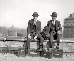 Washington, D.C., 1924. "Van Tine &amp; Johnson." Harry Van Tine and Joe Johnson in a photographic survey of Washington-area lensmen. View full size.
International Newsreel Corp.That's confusing - if they're newsreel lensmen, why the still cameras, a 4x5 Graphic and 5x7 Graflex? I'll need to dig into this one.
[International Newsreel was a photo agency whose pictures appeared in many newspapers. - Dave]
Perfect typesThese look exactly like the guys you would see in a 1930s movie, brandishing flash cameras, with a card reading "Press" stuck into their hatband.
Graflex shootersThe camera between them appears to be an early Graflex single lens reflex.
Walking all over town  those shoes could use a spit shine.
Could it be Lincoln&#039;s church?The building in the right background is the old Masonic Hall on New York Avenue, which would seem to put these two gentlemen on the roof of the old New York Avenue Presbyterian Church, the church attended by Abraham Lincoln, which was torn down in 1950. I'm not sure where they'd fit up there, however--possibly on a ledge on the clock tower? Perhaps it's more likely that they're on the roof of one of the buildings nearby on H Street, such as the Times-Herald Building, which would be very fitting. 
Pappy Van Tine


Washington Post, May 2, 1968.

Lensman Harry Van Tine Dies.


Harry M. Van Time, who snapped exclusive photos of Harry K. Thaw escaping from a mental institution in 1915 and took the first still pictures of actress Mary Pickford, died Tuesday at Washington Hospital Center after a two-month illness. He was 82. 

Mr. Van Tine, known throughout his professional life as "Pappy" and "Van," retired in the 1950s after 40 years with International News Photos. He was dean of the White House News Photographers Association and one of its founders.

Born in Beacon, N.Y., he was working for a newspaper chain in the Hudson Valley when Thaw, who had murdered the famous architect, Stanford White, escaped from Matteawan State Hospital.

His photos helped him to land a job in New York soon after that and by 1914 he was working for INP, covering championship boxing matches, taking photos from early and makeshift airplanes, and photographing Barney Oldfield winning the Sheepshead Bay auto race.

He took still photos of Mary Pickford when she was a young girl appearing in "The Call [Song] of the Wildwood Flute" and he was there with his camera when a midget was planted into J.P. Morgan's lap.

Mr. Van Tine came to Washington in 1917 on assignment, covering the arrival  of French Marshall Joffre and Italian Minister Marconi, and decided INP needed a Washington bureau. He became that bureau and was with it from then on. 

Things were more casual then around the White House and the photographers harder to handle. Mr. Van Tine wanted to get a photo of President Wilson basking in the sun on the White House lawn, so he hid in a load of hay that was headed for sheep which then grazed behind the White House. But he was discovered by Secret Servicemen.

Mr. Van Tine was the first vice president of the White House News Photographers Association. He served later as president and was for ten terms the organizations secretary-treasurer.

Mr. Van Tine, who lived at the Roosevelt Hotel, 2101 16th st. nw., is survived by two granddaughters, Mrs. Cyril J. Pittack, of 601 Four Mile rd., Alexandria, and Mrs. Al Kimbrough, of Reno, Nev.
Van Tine&#039;s cameraHarry Van Tine was my great grandfather. We still have that camera. 
Thank youThis is the first time I have been able to see my Great Grandfather Harry
(The Gallery, D.C., Natl Photo)