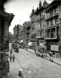 New York circa 1900. "Chinatown -- Mott Street." 8x10 inch dry plate glass negative, Detroit Publishing Company. View full size.
The view todayMany of the buildings are still there, and looks like as fun a place as ever to explore!
View Larger Map
Interesting architexture The railings on the buildings on the right hand side of the street are reminiscent of the ones in New Orleans.
[A delight to the touch as well as the eyes. - tterrace]
I should have used spell-check...:-)
Where Dr. C.S. Bok livedThis postcard is in my family’s collection. Dr. Chu Soule Bok lived on Mott St. near the place pictured on the postcard which was sent in 1911. Dr. Bok and my grandfather C.M. Austin became friends after meeting at Centenary Collegiate Institute in Hackettstown, NJ, in 1891. Several of C.S. Bok's letters are also in the family collection.
MSGHalf an hour after looking at this Shorpy photo, I felt the need to look at Shorpy again.
Am I seeing things?In the street, to the front and to the right of the horse-drawn wagon, there is something on the road itself -- a puddle, a piece of debris, something -- and the odd thing is it looks like it has letters on it?  I see "ROBDEV"?  It really does look like a puddle, but if the letters were a reflection, wouldn't they be backwards?
I also thought that maybe the photographer playfully left his name on the spot?
Dunno, would love to hear what y'all think.
[The thing you're seeing is a manhole cover with holes in it. -Dave]
Across the streetIs the WO HOP Chinese restaurant.  A world famous institution since the 1930s, for all late night club-goers, at 17 Mott Street.  This view is facing south.
Chinatown: 1900"And tell me what street
Compares with Mott Street
In July?
Sweet pushcarts gently gliding by.
The great big city's a wondrous toy
Just made for a girl and boy.
We'll turn Manhattan
Into an isle of joy."
-Richard Rodgers and Lorenz Hart 
HeadlightThe candle lantern on the front of the horse cart should be adequate at 5 mph.
Step stylesIt is a fascinating picture, but one thing that struck me of all things is the variety of styles of steps, and that most are constructed out of wood, for a city block made of brick and stone, I thought this a little odd, not what I expected to see.
(The Gallery, DPC, NYC)