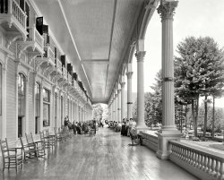 Lake George, New York, circa 1908. "Grand piazza, Fort William Henry Hotel." 8x10 inch dry plate glass negative, Detroit Publishing Company. View full size.
That &quot;Deck&quot;OK, the veranda needs some work up top but the craftsmanship that laid it down was superb. Just think of the men on their hands and knees putting it together as master "floor people" with planks out of the mill.
Obligatory &quot;Burned to the Ground&quot; Statement"On the morning of June 24, 1909 at the onset of the summer season, the hotel was completely destroyed by fire."
http://www.fortwilliamhenry.com/history/
But it WorksCorinthian columns, Colonial Revival spindles, Victorian corbels.  A beautiful explosion of architecture.
No Adirondack Chairs in SightAlthough Lake George is today often (usually?) considered part of the Adirondacks.
My how things have changedThe idea that people would go on vacation to an elegant hotel to simply sit on a veranda (and a very beautiful one at that) has gone the way of the horse driven carriages that brought them there.  Nowadays people feel the need to "do something" on their vacations, instead of simply enjoying doing nothing.
How sad!to hear that this wonderful hotel would be gone the next year.  The Hotel Del Coronado in San Diego is an all-wooden hotel still in operation since the 1880s, due to its extensive sprinkler system.  In case of a fire there, you're more likely to drown than to burn!
Passion On The Porch
&nbsp;&nbsp;&nbsp;&nbsp;&nbsp;Prunella, although she has some trepidation, holds back her tears as her mother and Aunt Agatha convince her that the handsome bachelor, Melville Van Korster, would be the perfect husband for her. 
&nbsp;&nbsp;&nbsp;&nbsp;&nbsp;Meanwhile sitting in the background is Chasity Corbona who has her own plans for the fair haired Melville.
(The Gallery, DPC)