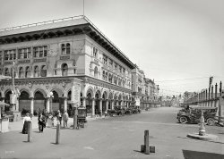 Sunny Venice, Calif., circa 1912. "Hotel St. Mark and street." At the Aquarium on the pier: "Seal fed daily at 2 p.m." 5x7 inch glass negative. View full size.
Bizarre Service?Note the partially visible sign on one of the vehicles parked on the viewer's right.  I suppose it is advertising some local cabaret, but what's visible suggests that, for a suitable fee of course, a quartet motors to your home to sing the latest ditties for your edification and amusement.
["At the" would seem to preclude the latter. - tterrace]
I agree, now that I can read the fine print.
So Where&#039;s the Cat?Lower left corner: Tweety's owner!
Not too bad!I knew Venice was built with canals, but I did not know that they also tried to make it resemble the original Venice architecturally as well. It's not a bad imitation, actually, at least for this block or so.
Hotel St. Mark is long goneBut its next door neighbor seems to still be there (although unfortunately stripped of much of its fancy gingerbread).
Venice Silent Film Spot - Keaton, Chaplin, LloydThe great silent film comedians Buster Keaton, Charlie Chaplin, and Harold Lloyd all filmed frequently in Venice, as I explain in my books.
Here is a movie frame from Buster Keaton's The High Sign that shows the Hotel St. Mark in the background.  As I show in my book Silent Echoes, Keaton filmed many scenes at this locale.
This blog post below tells about Chaplin filming Kid Auto Races in Venice in 1914, his first screen appearance as the Little Tramp.
http://silentlocations.wordpress.com/2011/10/31/chaplins-kid-autos-they-...
John
John&#039;s Great Blog!John, I've looked at your blog many times, and greatly enjoyed it. The filming locations of those great silent flicks is fascinating to me. Just wanted to say that your work is much respected and appreciated!
More Chaplin, Keaton, and Lloyd in VeniceThe Venice Events board to the left of center lists several attractions where the great stars filmed.  
First on the list is the Venice Aquarium, which appears behind Charlie Chaplin during this shot from The Adventurer (1917) (see below - the sign behind him reads "MUIRAQUA" - it's the back of the AQUARIUM sign).
Next on the list is The Venice Miniature Railway, where Harold Lloyd filmed at least two movies.  You can read about the railway at the end of this blog post.
http://silentlocations.wordpress.com/2012/09/25/harold-lloyd-by-the-sad-...
Lastly, the Venice Plunge plays a major role in Buster Keaton's early MGM triumph The Cameraman (1928).  You can read about the plunge at the end of this post.
http://silentlocations.wordpress.com/2012/07/07/buster-keatons-the-camer...     
Not much leftThere's more of this gingerbread left along Main Street, just south of the Santa Monica line. But only a few fragments.
I see Venice almost every day, and it's striking how much uglier it is now. It's like the pod people took over.
+104Below is the same view from November of 2016.
(The Gallery, Cars, Trucks, Buses, DPC)