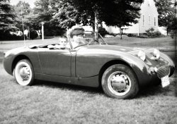 Dad and me in another one of his cool cars, 1965ish.  He would buy one and fix what was wrong; some kept breaking a lot, but he enjoyed working on stuff. View full size.
Amphibian in the UKThese were always 'frog-eye' Sprites on this side of the Atlantic...
American Austin Healey SpriteI bought my Bugeyed Sprite, a 1960 model, in 1961. Why, I don't know! Mine had the fairly rare fibreglas hardtop which greatly improved the looks and warmth in Illinois winters. I worked in a small office only a few miles from home. Great little car for getting to work and back, even though central Illinois winters were not the best for such a little car.
I was already messing with old American cars, mostly attempting restoration and mild hot rodding so I did have a back up when the snow was headlight high! My first job but it didn't last more than six years. When the company moved to NY I refused to move. So I decided I'd sell life insurance. In reality I couldn't sell beer at a baseball game in July.
I soon realized those little 4-cyl high reving engines were not built for stop and go city driving. Had that poor little Sprite engine rebuilt twice. Still it didn't last. Ford was putting the new 289 in a small sports car. If they could do it I could too in my drive way using a large chisel, hammer, and hacksaw. Even back in the mid 60's I was a Chevy guy. So I bought a rebuilt 327/powerglide with 2-4 barrel carbs. A friend's dad had a portable welder so using masking tape, wooden shims. etc. I mocked up a square tube frame and in no time I was driving my little Chevy V-8 Sprite.
I swapped the 2-4 barrel set up for 3-2 barrels and drove the wheeels off that little maroon Sprite for several years before trading it for a 1933 Chevy.
Life was good in the 60's.
(ShorpyBlog, Member Gallery)