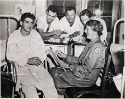 The note on the back says "Mrs. Conant & the boys at the Chelsea Naval Hospital in Chelsea, Mass. Mrs. C. drawing a quick pencil sketch of a wounded Marine or sailor recuperating therein. -  from a letter postmarked Cambridge, Mass, [12]/ 11/44"

Mrs. Conant was a friend of my father's when he attended MIT before and after the war. I think this may be Grace T. Conant, wife of James Bryant Conant, then president of Harvard University. The one photo I can find, taken in 1953 of the Conants, resembles the woman in this photo. Mrs. Conant corresponded with my father during the war, while he was serving with the Canadian Army. View full size.