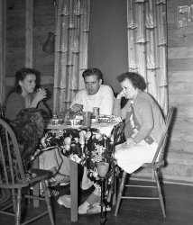 Well I am not sure if this is just the look of boredom, fatigue, or regret from what had happened the night before. From my negatives collection. View full size.
Regretthat his mom was invited on the trip. And Mom's wishing she'd stayed home, too.
Confused and upsetNo wonder: two teacups per person.  Not to mention the unsettling clash of teacups, tablecloth and curtains.
Morning fogMy guess is they all just woke up, are in no mood for chit-chat and the only one that any of them can tolerate at this point is the dog.  Not everyone can bounce out of bed singing and dancing and rarin' to go.  Some of us need to get used to our life all over again every day before we can sparkle.
(ShorpyBlog, Member Gallery)