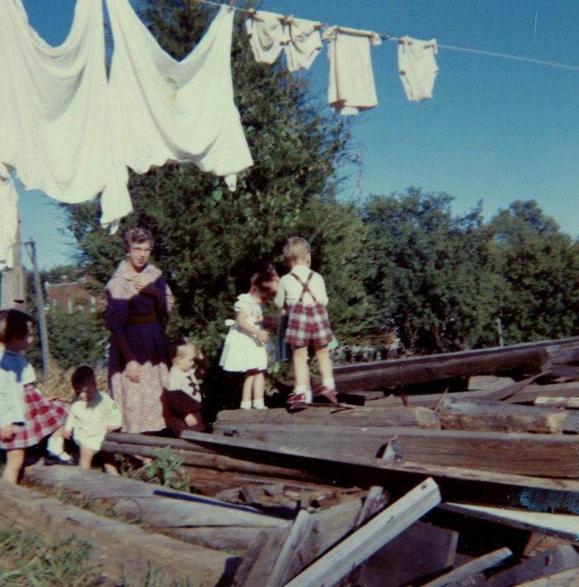 Kemptville, Ontario, probably 1960.
The pile of wood was, I think, the summer kitchen which had been attached to the house where I lived. This was a birthday party for one of the kids who lived next door to us. I'm not sure that clambering all over a pile of splintery, rusty-nail-filled wood is the safest of party games but I don't think anyone got Tetanus, so all is well that ends well. View full size.
I originally thought the boy in tartan was my childhood boyfriend, However, after getting an email from him out of the blue, some 45 years after I last saw him, he tells me it wasn't him.
