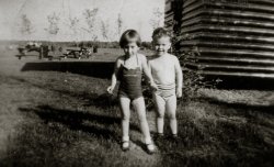 Brown's Bay Provincial Park, Ontario (near Kemptville), c. 1959. Me with my boyfriend, Michael, again. Who can resist a man who wears socks and shoes with his bathing suit? The "romance" lasted until my mother remarried and we moved to Ottawa, in 1963.
I still remember that bathing suit. Red with a pin-stripy ruffle around the top. View full size.
UPDATE! I got an email from Michael last night, out of the blue. It's been about 45 years since we last saw each other. He wrote "What a way to trigger some great memories from my young years in Kemptville. I believe that is me in the first picture but not in the second [the "Lover's Quarrel" one]; I guess you had another boyfriend [I responded that the WAS only one boyfriend for me, back then and it was Michael!]. You were responsible for my first spanking in kindergarten (actually having my hand slapped) when I got upset that you weren't sitting beside me in class."
I didn't remember that at all... But it was nice to know that at SOME point in my life I was a heartbreaker...
The Feeling Is MutualThe attraction must have worked both ways, since you are also wearing socks and shoes.  Maybe it was just an attempt to protect your feet from those frigid, even in summertime, Canadian waters???
(ShorpyBlog, Member Gallery)