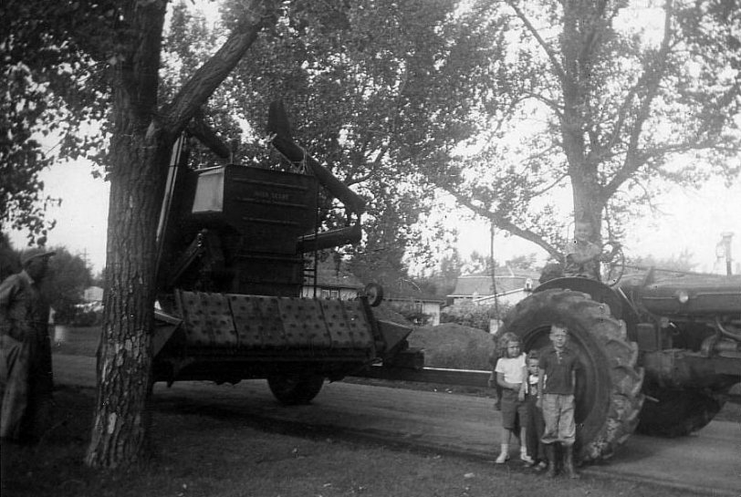 My Dad's brand spankin' new 1956 JD 65 combine and his showroom Co-op E4.  Those had to be the two smoothest running 6 cylinder engines on Earth, at the time.  That's me on the tractor seat, my Dad off to the left, one of my gangster friends and two little neighbor kids.  What a big deal that was!  That combine seemed so huge.  I can still hear that nice old Herc revving up.  It would always correct itself for over speed on the initial speed-up.  That outfit was my Dad's pride and joy.  I was lucky enough to be able to haul grain for one season from Dad running that pair.  I would pay dearly to be able to haul one more load away from him in our 1950 Mercury 1 ton.  Taken in from of our home at 814 Pheasant St., Grenfell, SK, where I still live! View full size.
