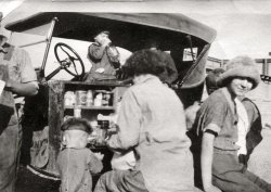 The fellow's elbow on the far left belongs to one of the guys looking at the map in this photo. This is what the rest of the family was doing. Dig the bowl cut on the little guy. View full size.
No fast food!Mom was clearly feeding her hungry brood while Dad and Uncle Joe were trying to figure out how to get to Timbuktu. Without any drive-throughs in those days, making a meal on the side of the road was very common.  I am not nearly old enough to be in this family (my parents are roughly the age of the little boy with the bowl cut) and I can remember bologna sandwiches at the side of windy Colorado roads on the way to Kansas. Ahhh, memories.
[There were plenty of roadside stands and greasy spoons with car service back in the olden days. - Dave]
(ShorpyBlog, Member Gallery)