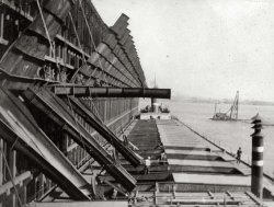 From a turn-of-the-century family photo album. I believe these are coal chutes, and they're loading the stores of a ship bound for sea.